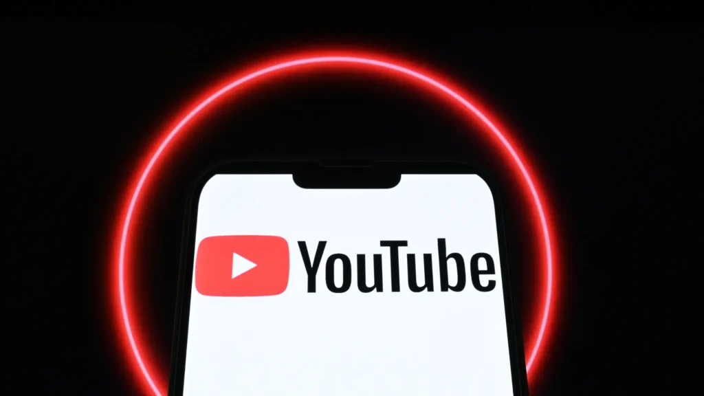 Smartphone displaying the YouTube app logo on a dark background with red neon light, representing Google Partner Match and new YouTube targeting tools.