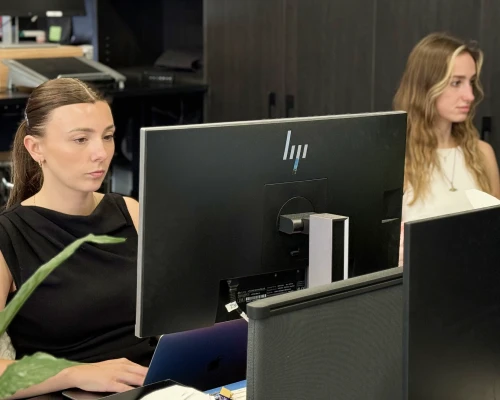 Two Online Marketing Gurus local SEO specialists working at their desks, with one focused on a large HP monitor in the foreground.