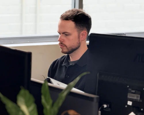 An Online Marketing Gurus SEO link building specialist focused on his work at a multi-monitor desk.