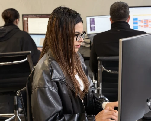 An Online Marketing Gurus content marketing consultant working at her desk in the agency office, with colleagues at their workstations in the background.