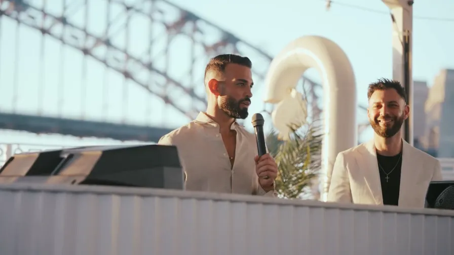 OMG founders Andrew Raso and Danny Andrawes speaking at an event with the Sydney Harbour Bridge in the background