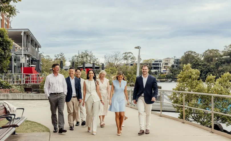 The PMC Property Buyers team walking together along a Brisbane riverside path