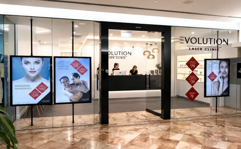 Evolution Laser Clinic shopfront with promotional displays and a reception desk visible through glass